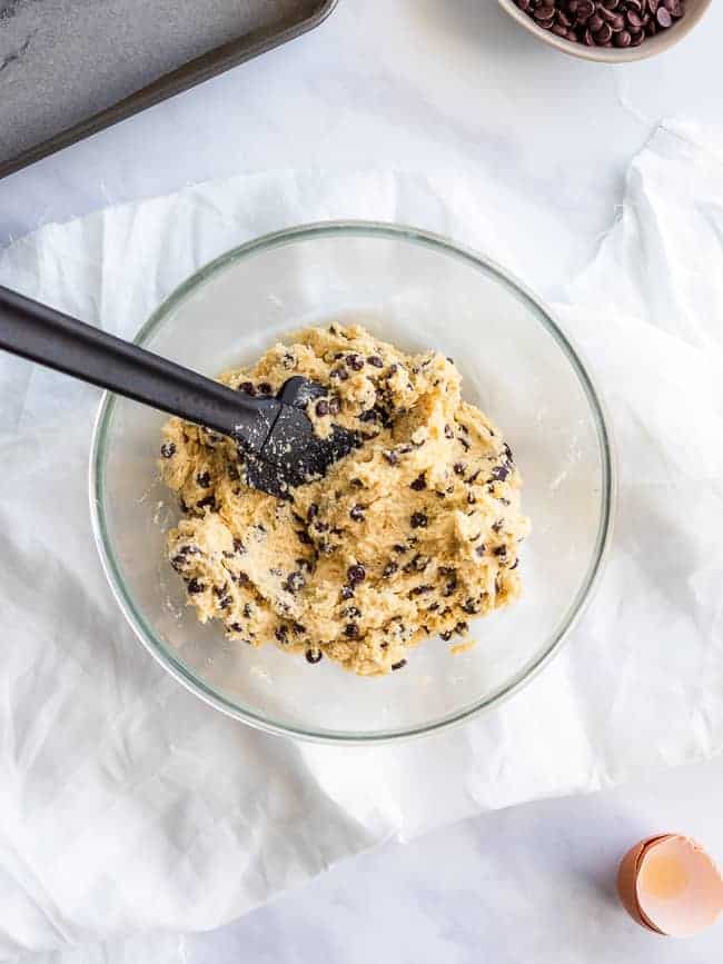 glass mixing bowl on white table cloth filled with cookie dough