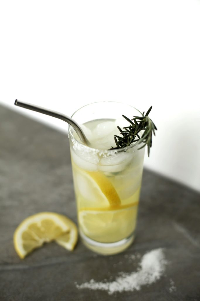 glass with a metal straw and a sprig of rosemary